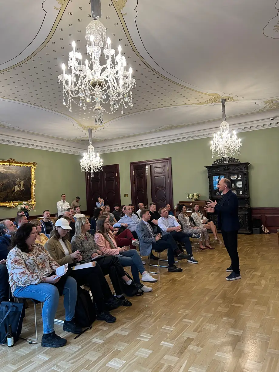 A BAICA session in Riga: an audience seated in a hall, listening to a speaker.